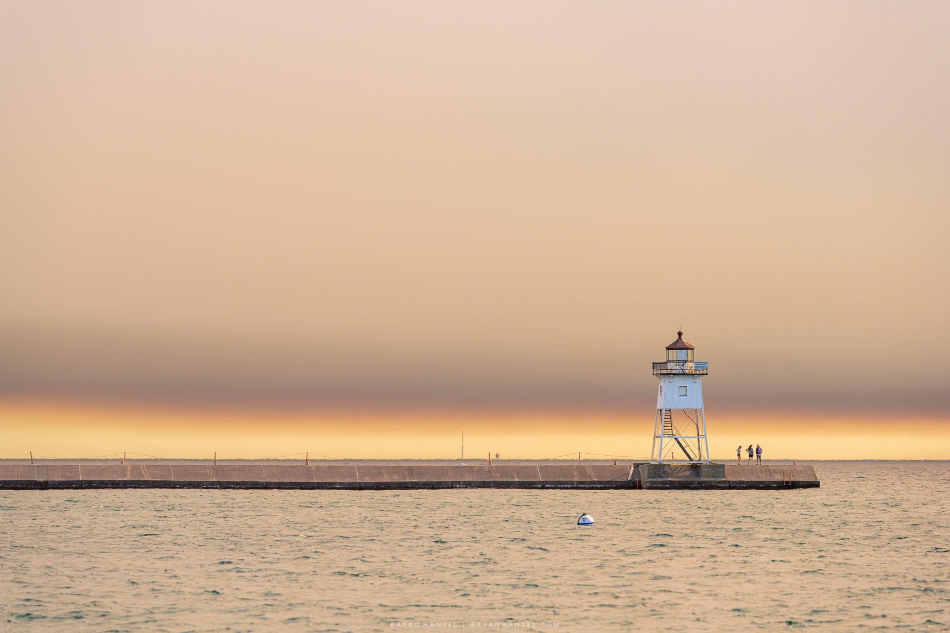 Grand Marais Lighthouse stands beneath a broad layer of wildfire smoke stretching across the sky above Lake Superior.