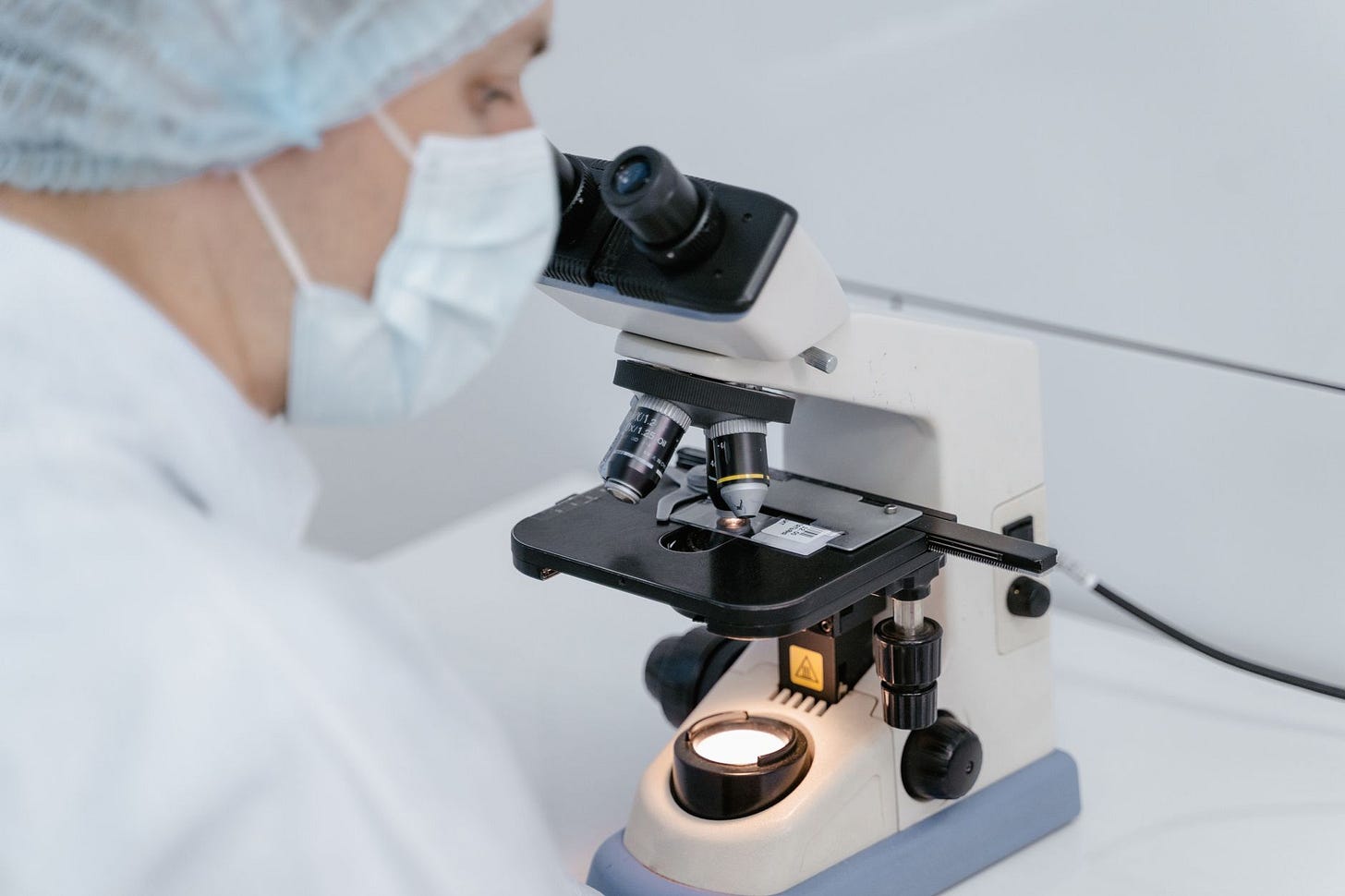 Photo by Tima Miroshnichenko on Pexels Scientist using a microscope in a laboratory setting, wearing protective gear. (stock photo)