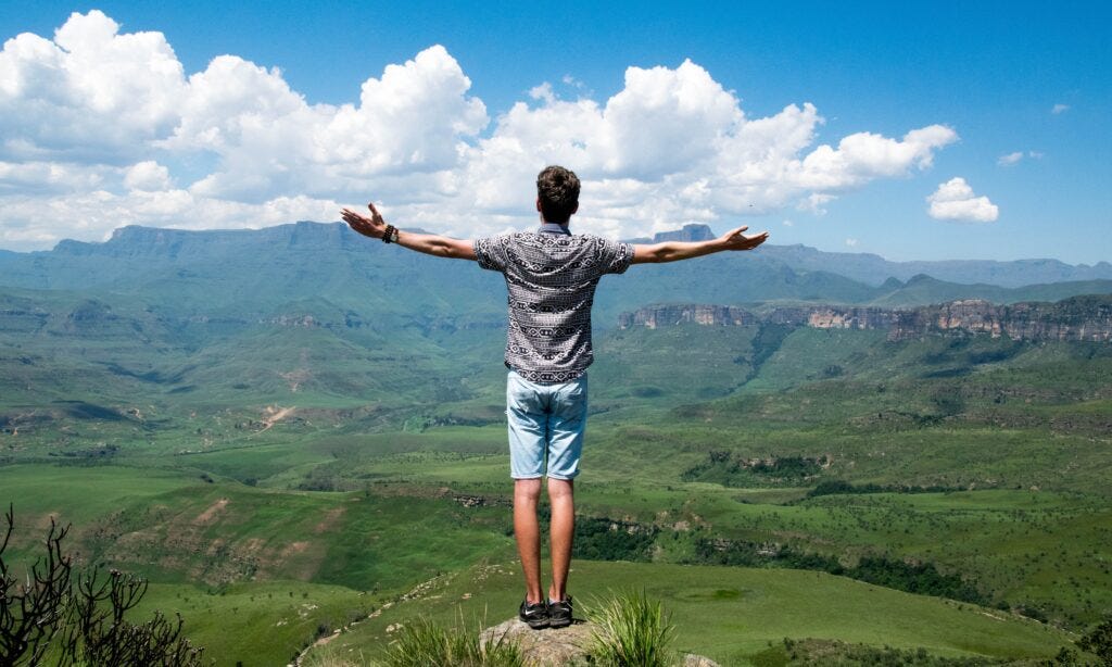Man standing on cliff embracing best investing