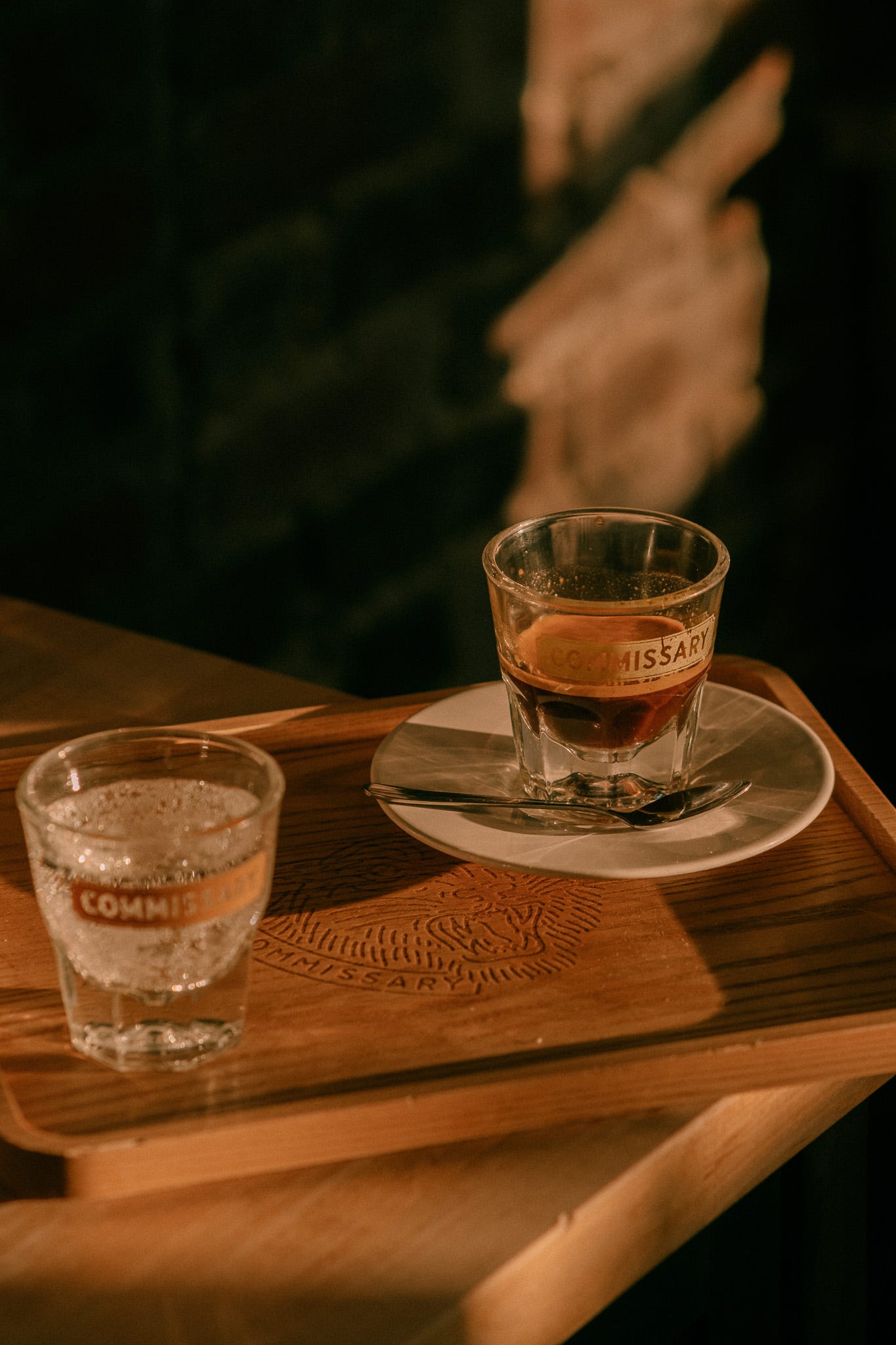 Wooden coffee tray with a shot of espresso in one cup and soda water in the other