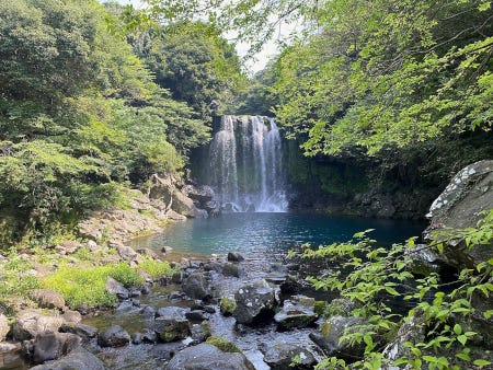 Une cascade sur l'île de Jeju, entourée de verdure et dépourvue de toute présence humaine Une cascade sur l'île de Jeju, entourée de verdure et dépourvue de toute présence humaine