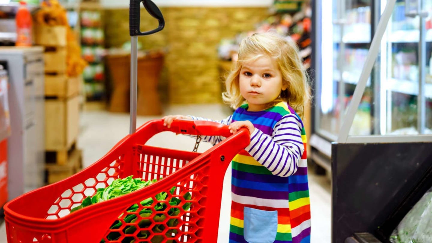 A toddler in action with a miniature grocery shopping cart. / romrodinka/iStock via Getty Images
