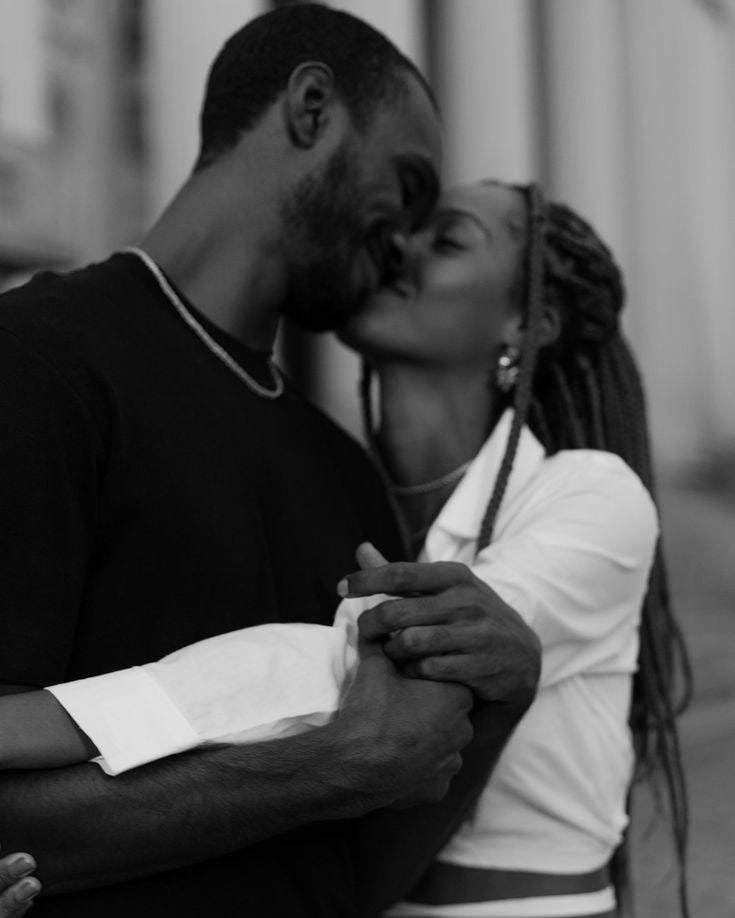 This may contain: a man and woman kissing each other on the street