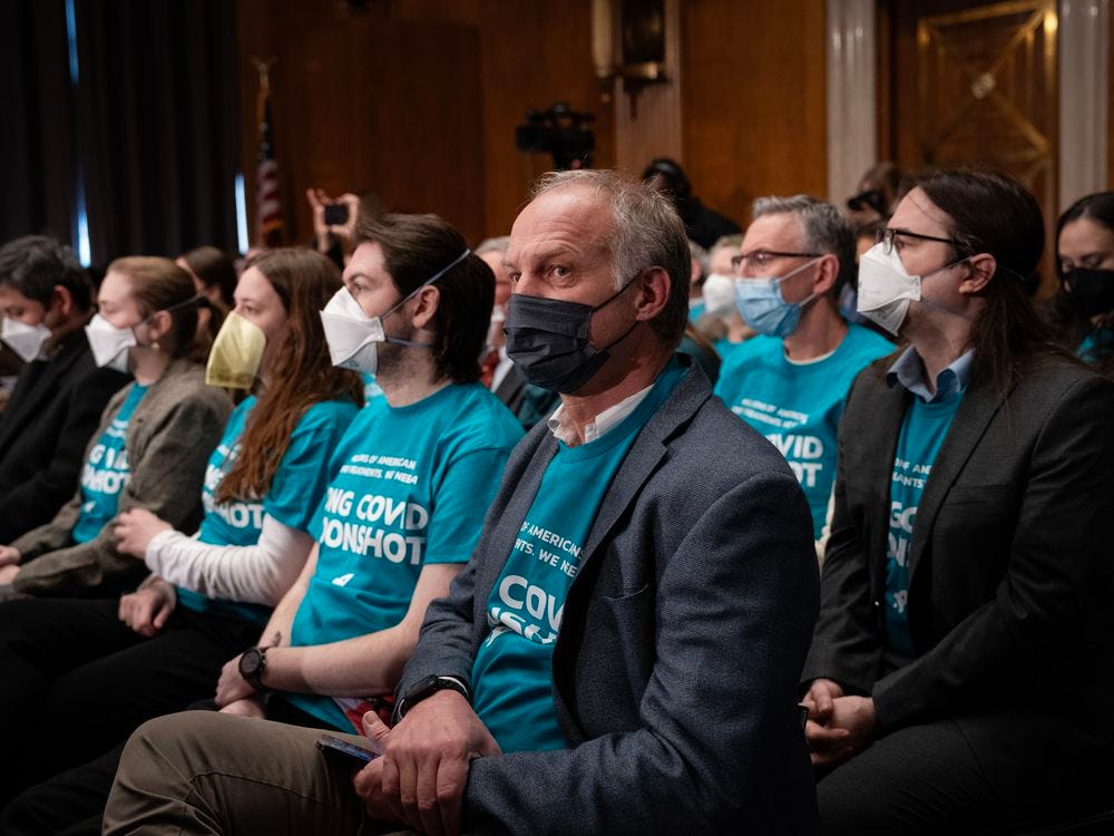 People with masks and blue t-shirts sitting in rows