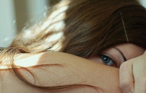 This may contain: a close up of a woman's face with her hair blowing in the wind