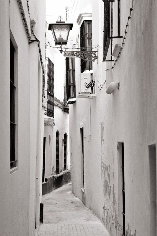 Callejón de Sevilla estrecho con paredes blancas y rejas en las casas Callejón de Sevilla estrecho con paredes blancas y rejas en las casas
