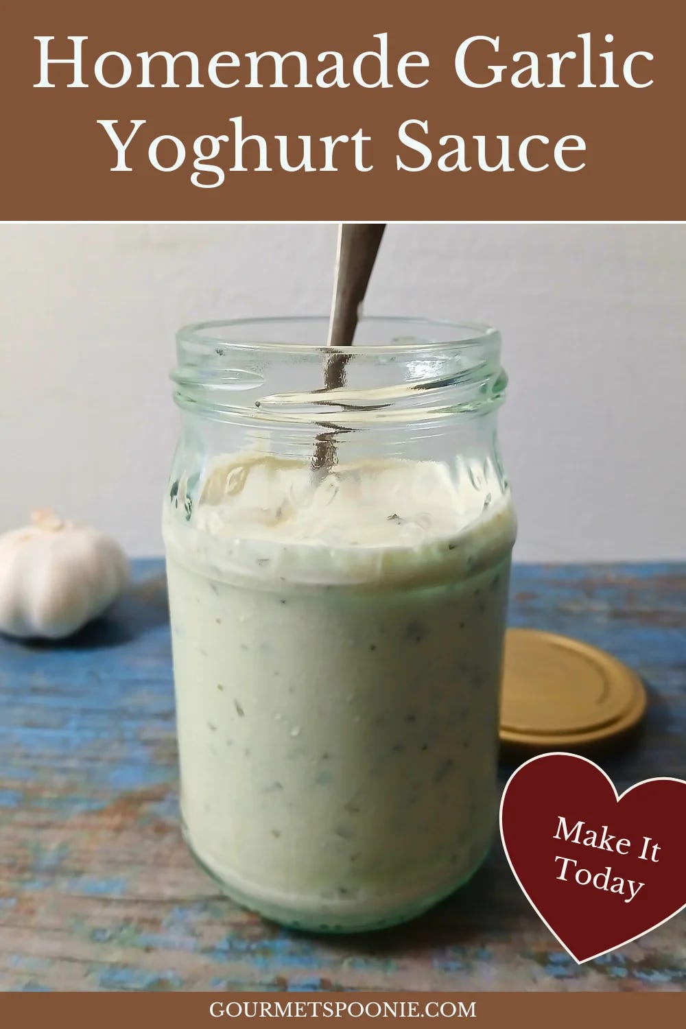 Creamy garlic yoghurt sauce in a glass jar with visible herbs.