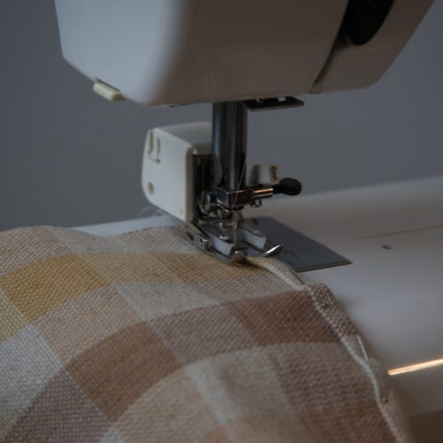 Handwoven fabric feeding into a sewing machine.