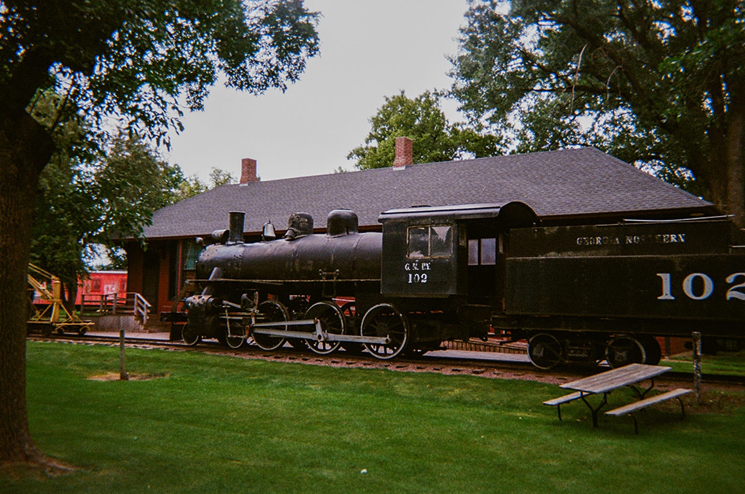 A black train with one passenger compartment on display on old railroad tracks