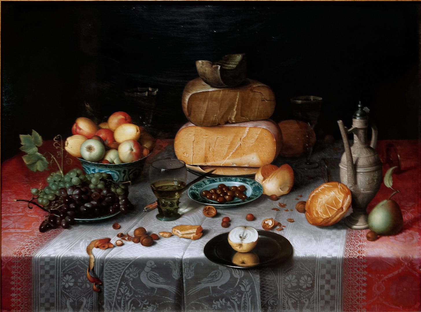 A detailed oil painting by Floris Claesz. van Dijck depicting a lavish still life arrangement on a white cloth-covered table. The composition features an array of cheeses, bread, fruit, and a pewter plate, with intricate textures and soft lighting that highlight the opulence of the scene. The painting, created around 1615, is a hallmark of Dutch Golden Age still life art.