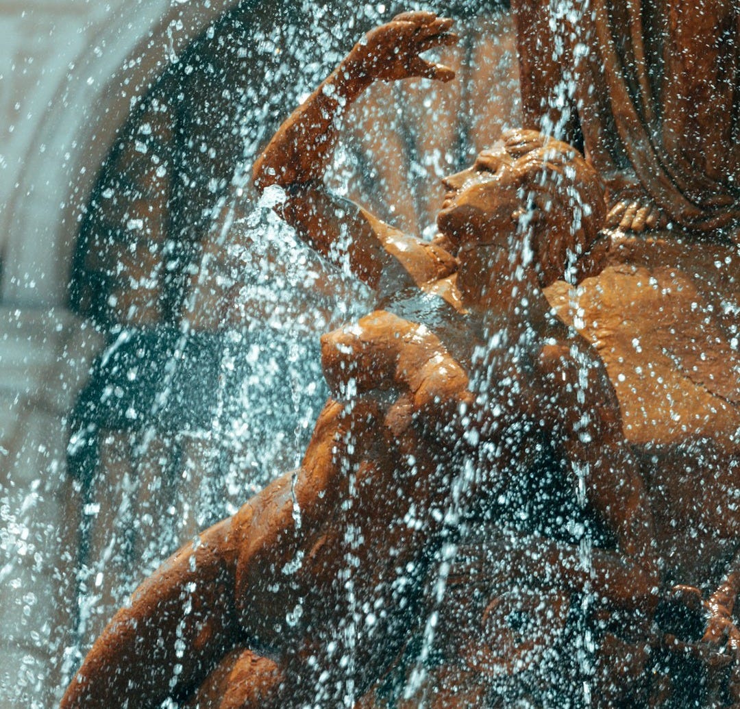 a statue of a woman holding a child in the water