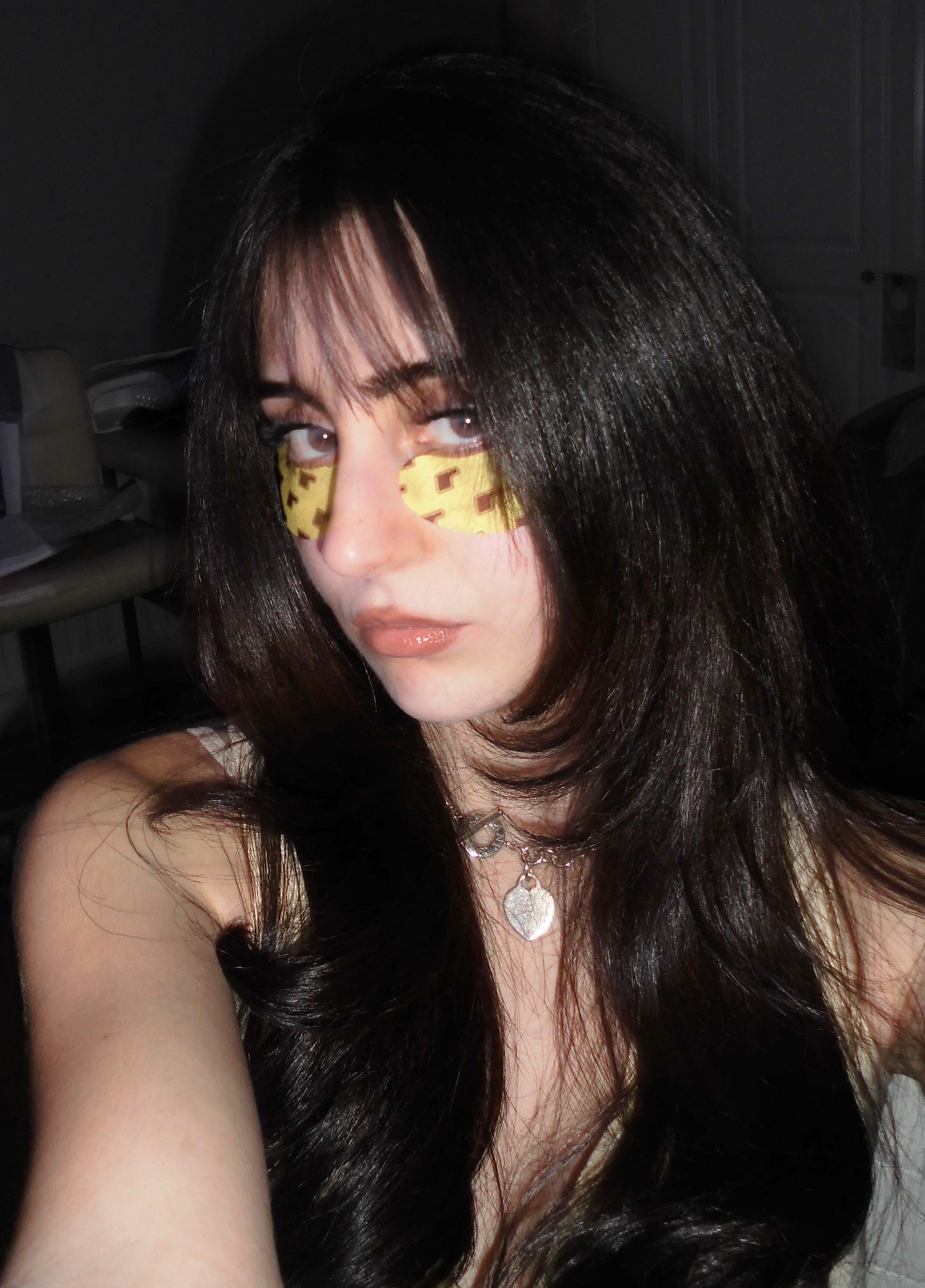 Beauty contributor Gia wearing the yellow and black patterned Rhode Peptide Eye Prep patches for under-eye depuffing and hydration.