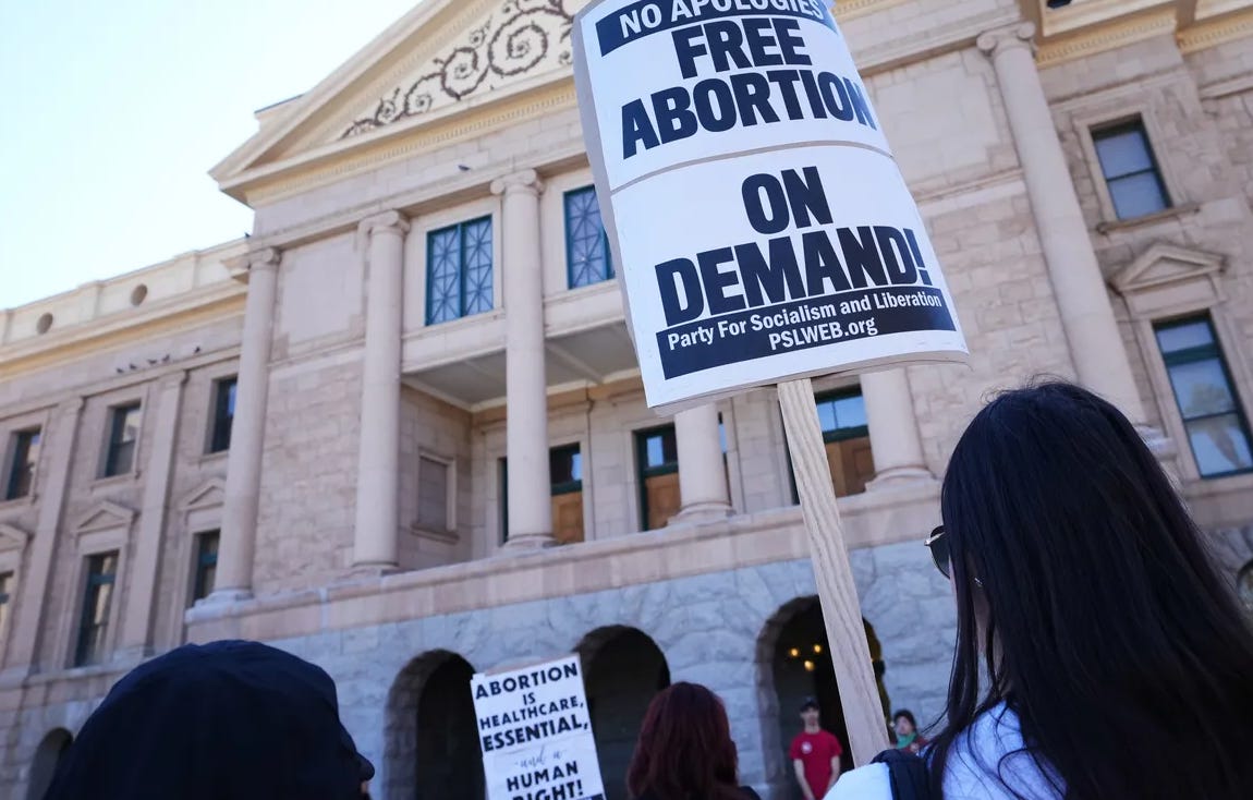 A group of people holding signs in front of a building

Description automatically generated
