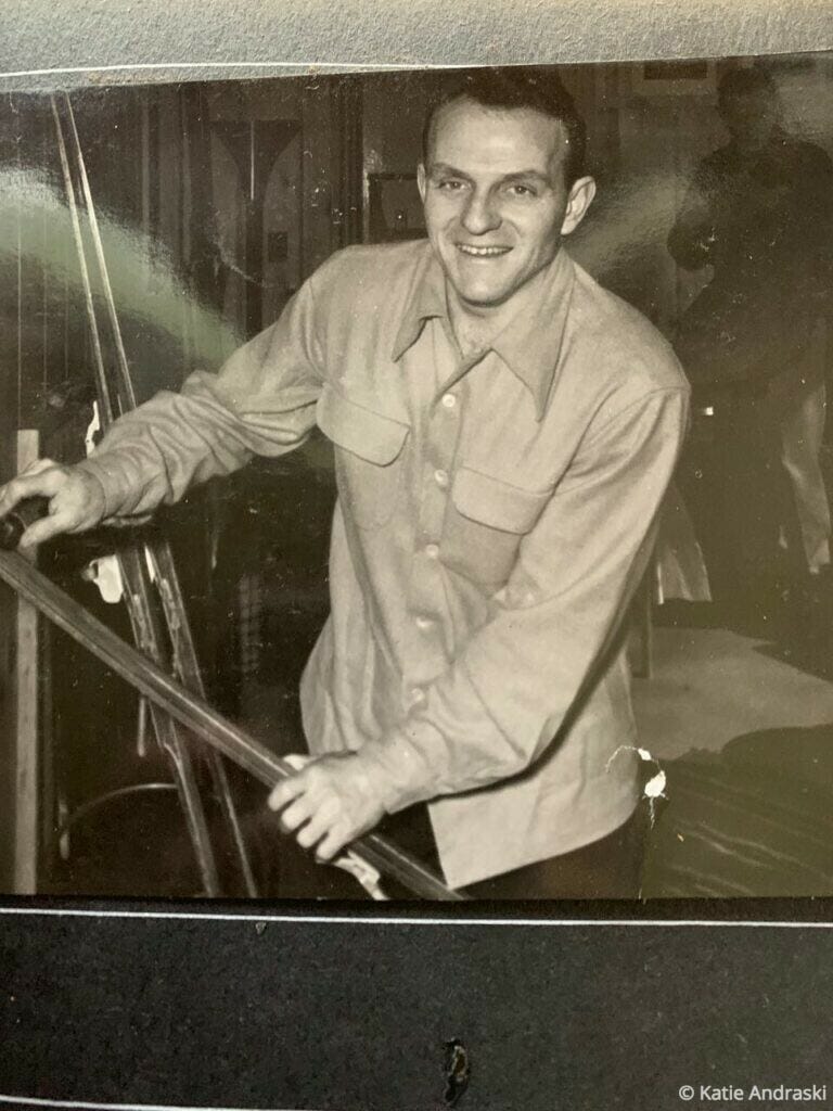 A smiling man playing pool indoors, holding a cue stick.
