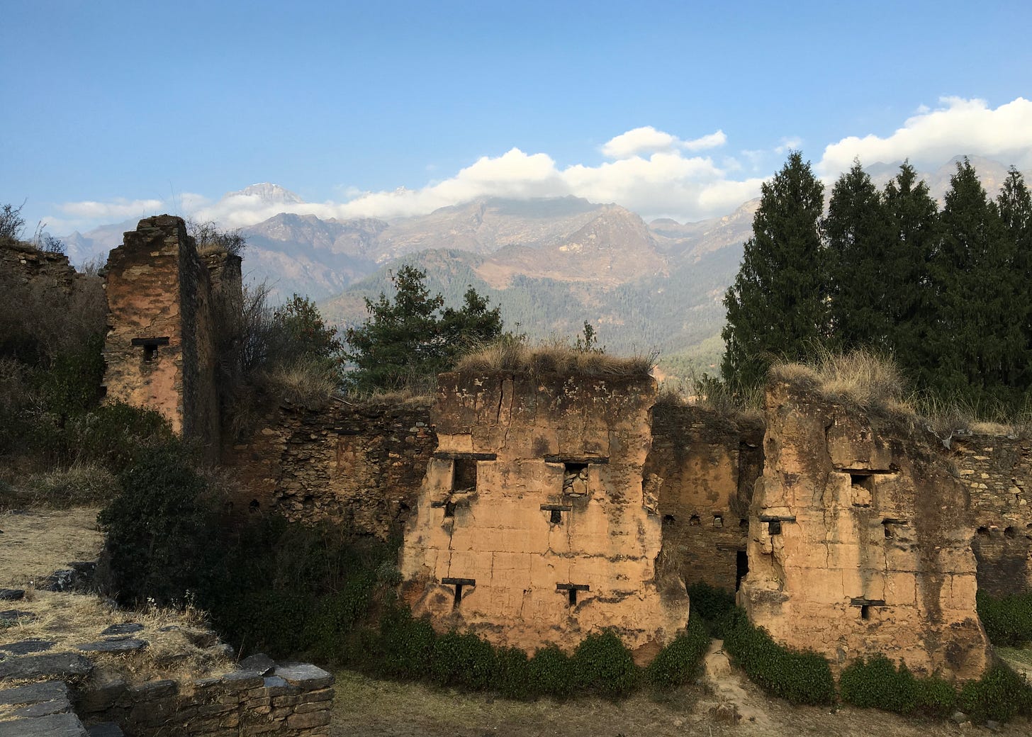 Ruins of a dzong in Bhutan set against a mountainous landscape.