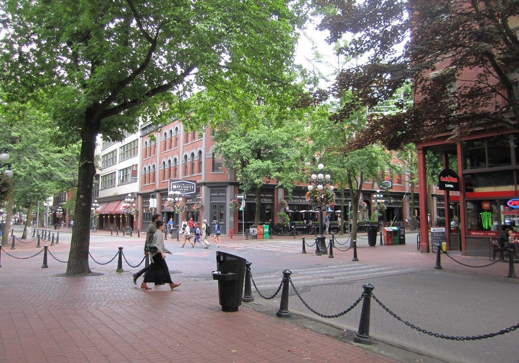 Pedestrians shop in a tree-lined plaza that's blocked off to vehicle traffic Pedestrians shop in a tree-lined plaza that's blocked off to vehicle traffic