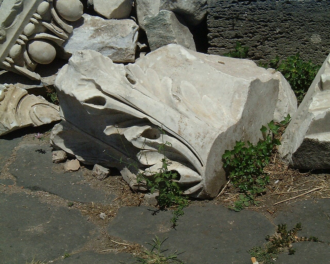 A damaged piece of white marble is lying on its side: you can just make out the carved leaf on it