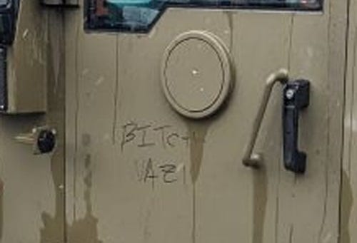 Enlarged photo of door of an armored truck with 'BITCH NAZI' scrawled on it in Sharpie. 