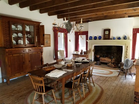 The Dickson Williams Mansion, a brick building with a white porch; the parlor, showing a round table surrounded by black chairs on a red oriental rug in front of a fireplace; the kitchen area, showing original north carolina furniture; bedrooms of the house, along with a portrait of General John Hunt Morgan sitting in a chair in a black coat with tall black boots; and the bed where he spent his last night.