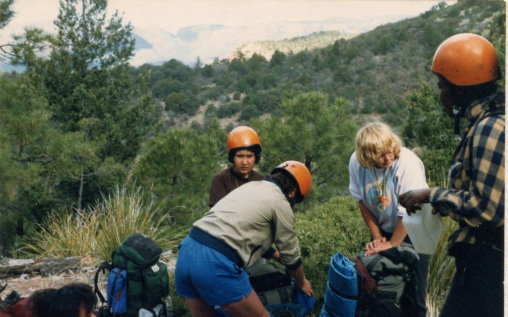 A group of teenage girls with backpacks and helmets on.