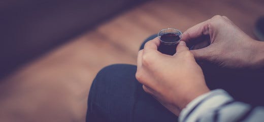 Young lady hand hold a red wine cup in Holy Communion. Wine in simple plastic cup, with blank copy space