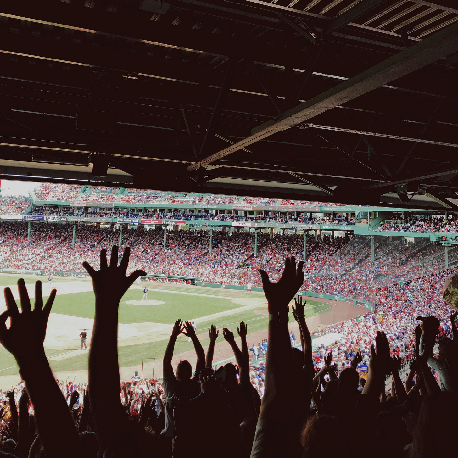 crowd of people raising arms to cheer at a baseball game crowd of people raising arms to cheer at a baseball game