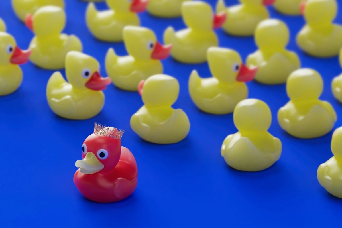 A red rubber duck wearing a crown faces forward, standing out against a crowd of yellow rubber ducks facing away, representing market leadership and a strong B2B unique value proposition. A red rubber duck wearing a crown faces forward, standing out against a crowd of yellow rubber ducks facing away, representing market leadership and a strong B2B unique value proposition.