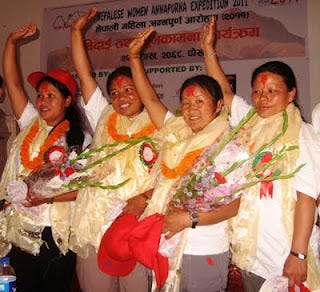 Four triumphant Nepali women wearing white silk scarves with red marks of blessing on their foreheads waving with their arms above their heads. Four triumphant Nepali women wearing white silk scarves with red marks of blessing on their foreheads waving with their arms above their heads.