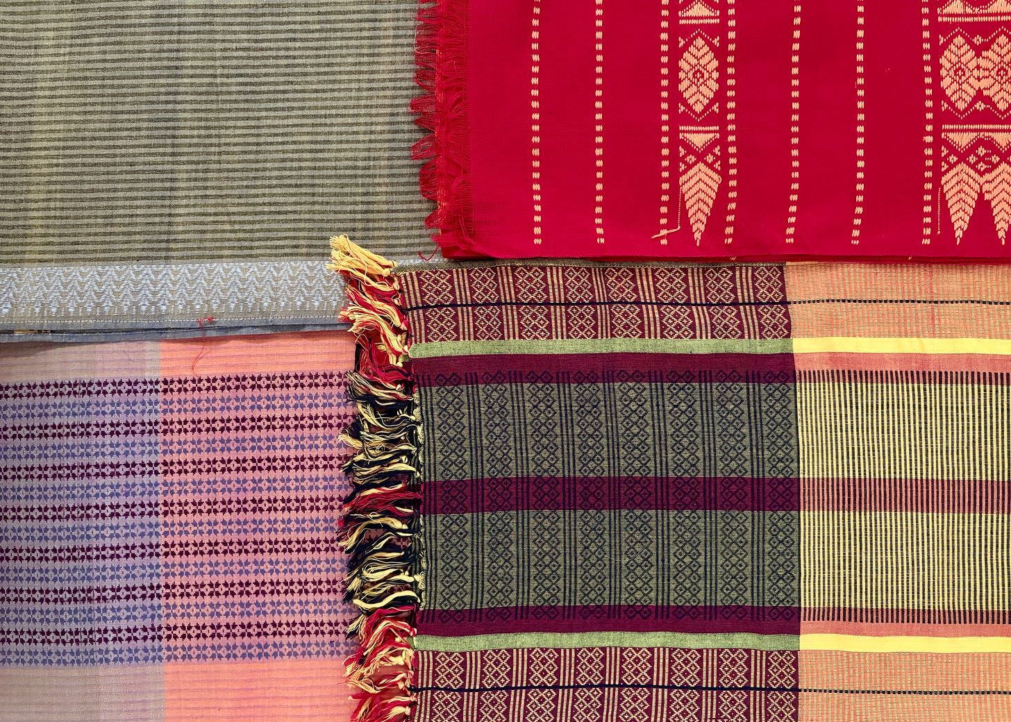 A collection of handwoven scarves from Assam displayed together, showing varied colors, stripes, and patterns representing different weaving traditions. A collection of handwoven scarves from Assam displayed together, showing varied colors, stripes, and patterns representing different weaving traditions.