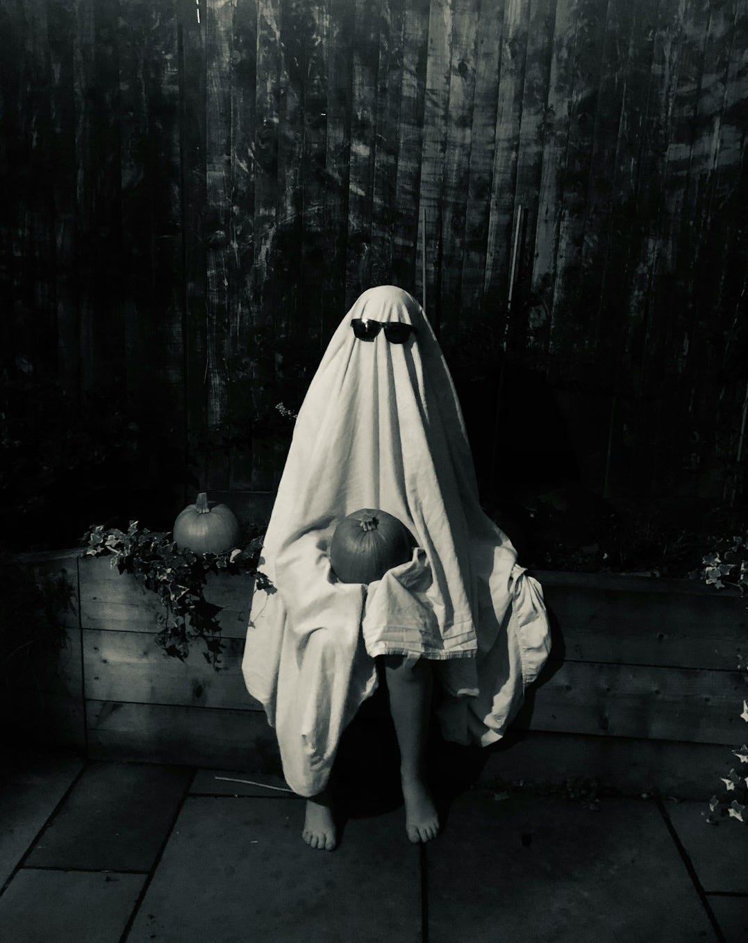 a young child wrapped in a blanket sitting on the ground