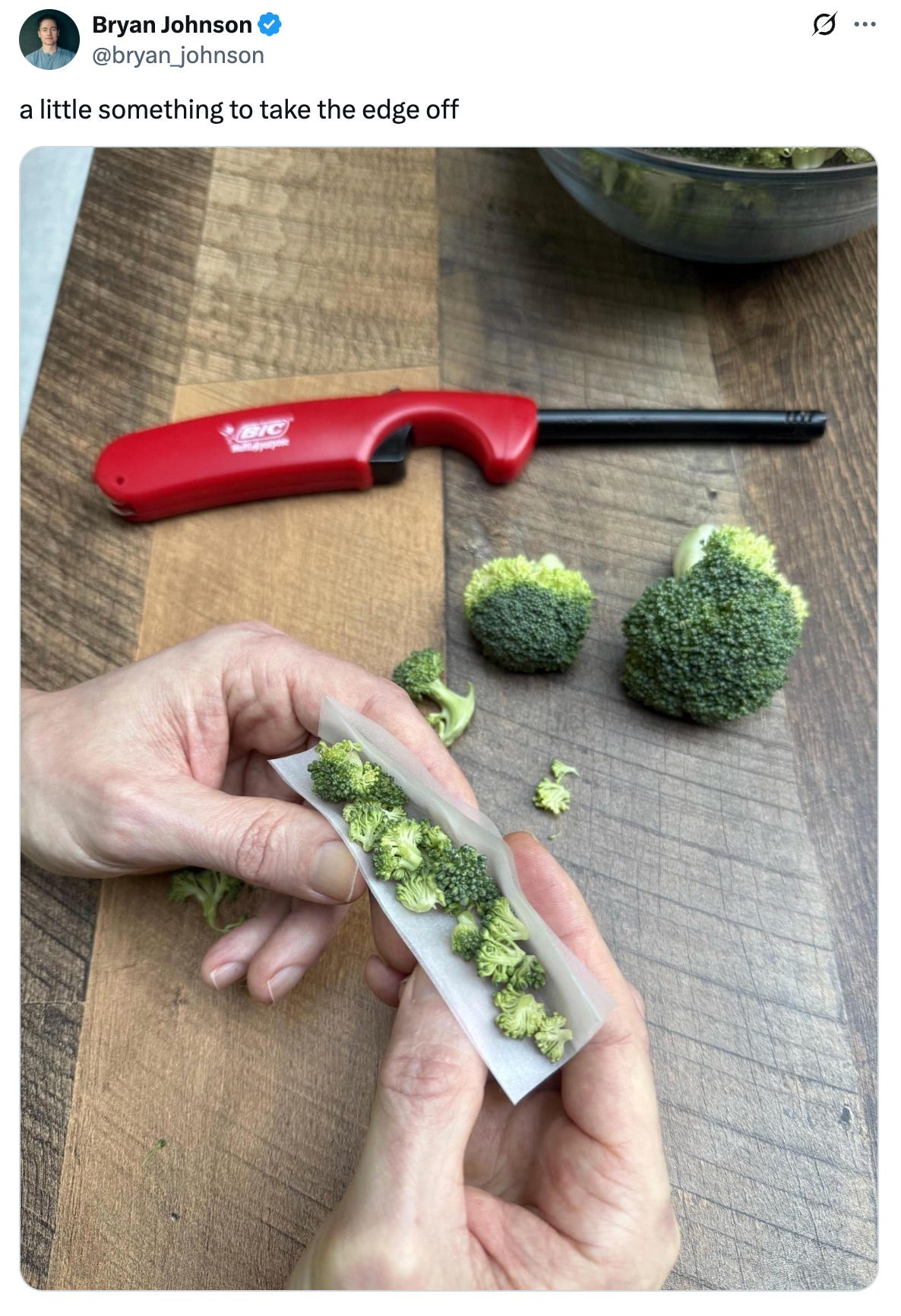 Tweet from @bryan_johnson that says "a little something to take the edge off" and features an image of him rolling up broccoli in a rolling paper. A lighter sits nearby