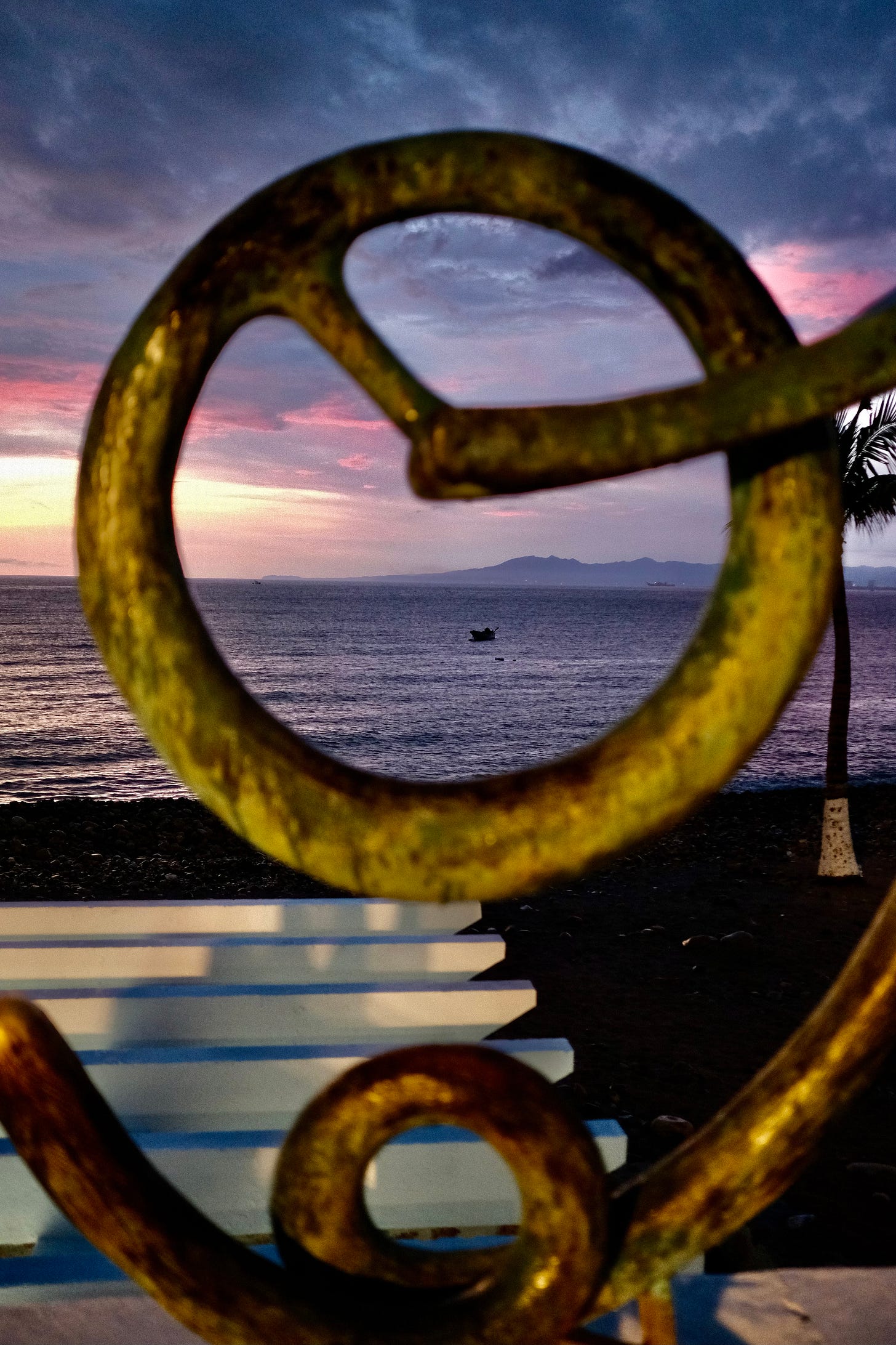 Photo of a boat on the sea through a statue at the Puerto Vallarta Malecon Photo of a boat on the sea through a statue at the Puerto Vallarta Malecon
