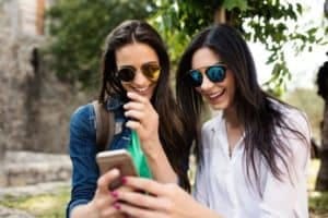 young friends watching viral social media video on mobile cell phone outdoors