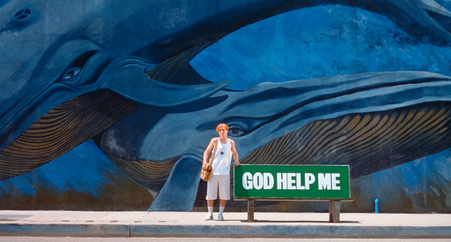 Nowhere | Still features a teenager against a painted mural background next to a bench that reads "GOD HELP ME."