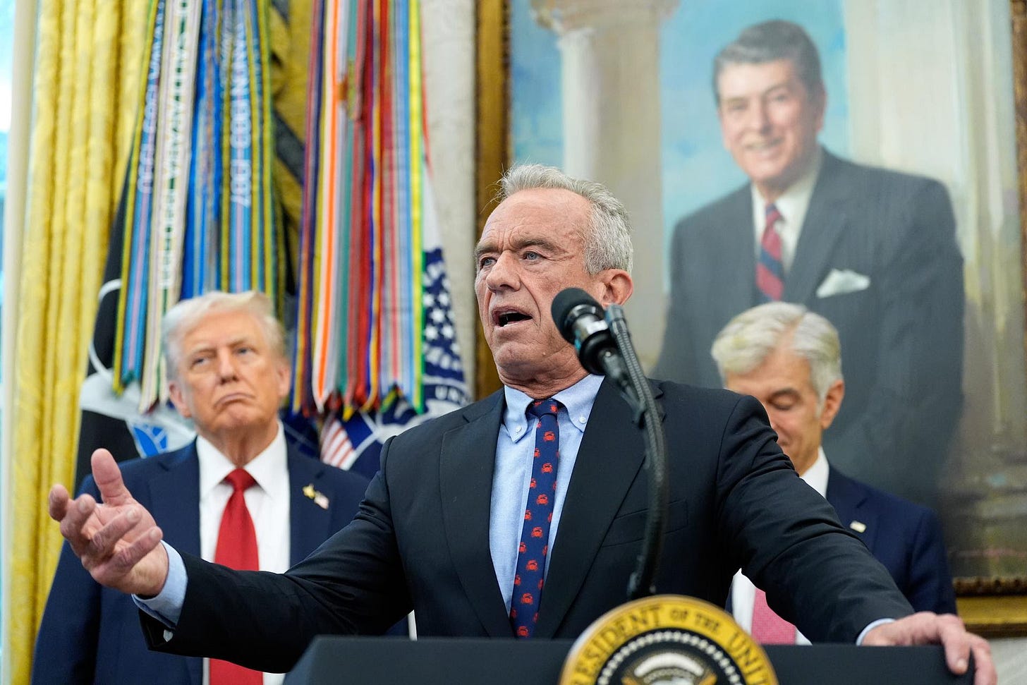 Secretary of Health and Human Services Robert F. Kennedy, Jr., speaks at the White House, Sept. 30, as President Donald Trump, left, and Mehmet Oz, Administrator for the Centers for Medicare & Medicaid Services, look on.