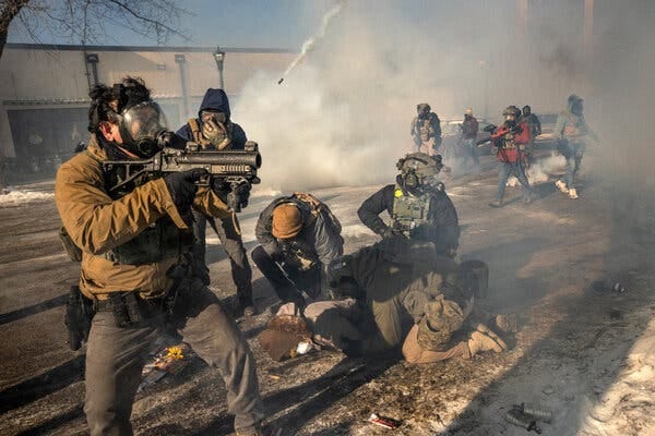 Federal agents in tactical gear and wearing gas masks pin down a person on the street in Minneapolis. Federal agents in tactical gear and wearing gas masks pin down a person on the street in Minneapolis.