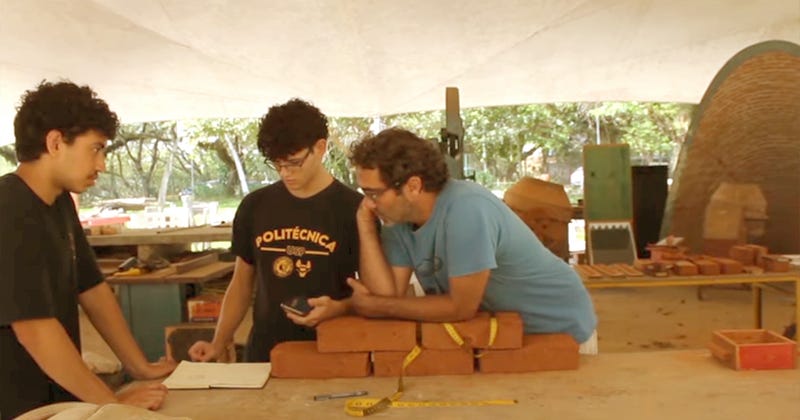 Três pessoas conversando e anotando numa mesa com alguns tijolos Três pessoas conversando e anotando numa mesa com alguns tijolos