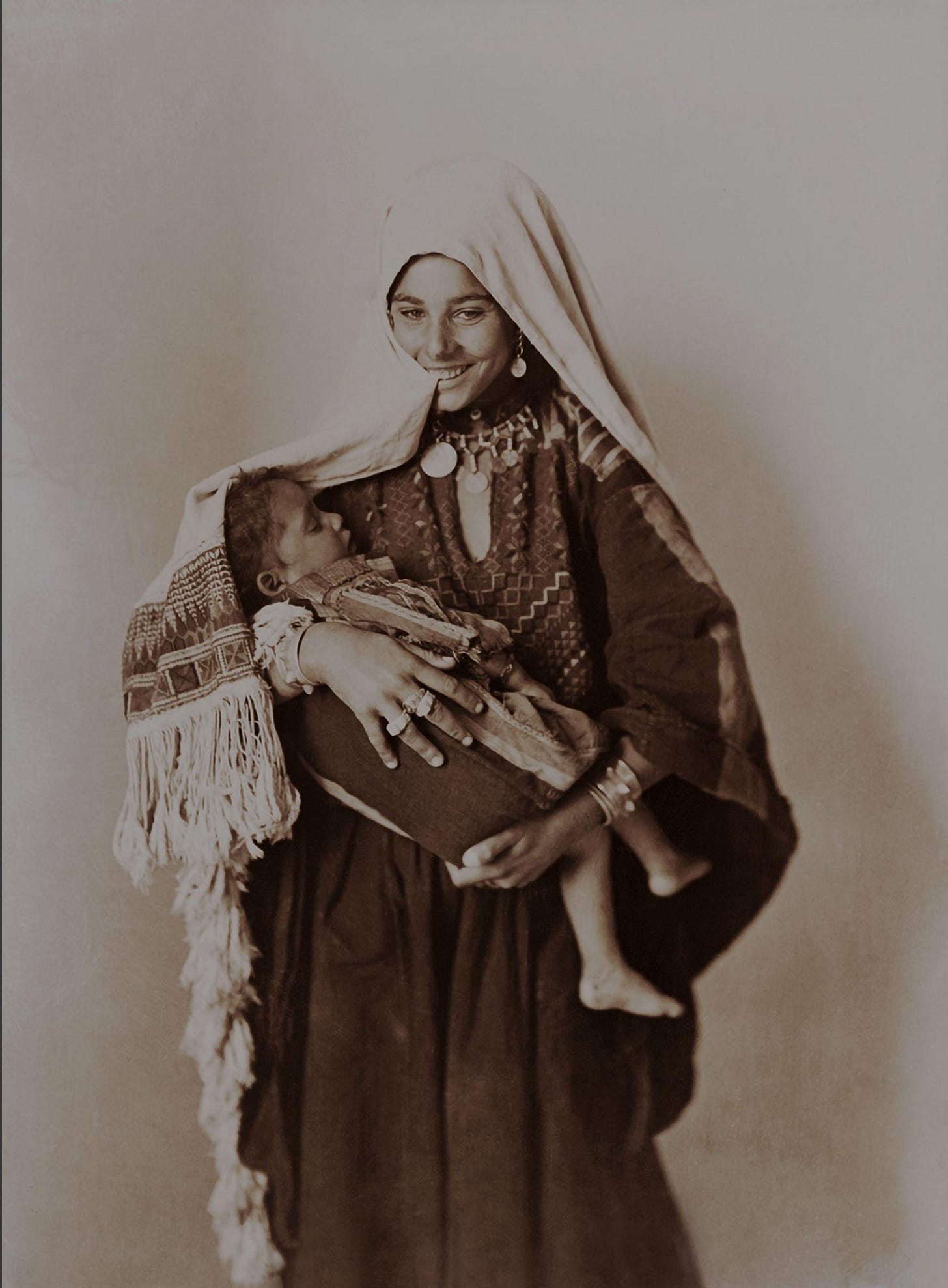 Smiling palestinian woman with child in traditional dress