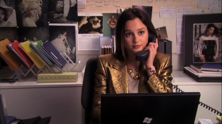 This may contain: a woman sitting in front of a laptop computer talking on a phone