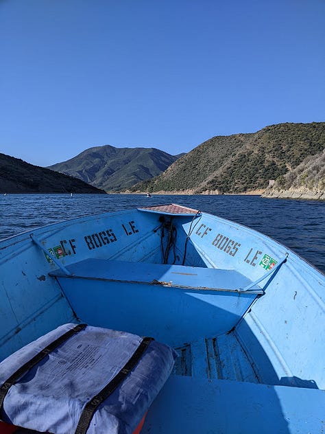 Photo of wrecked car, followed by five images of camping: Calm pyramid lake, a campfire, inside a boat on the lake, breakfast of eggs and chocolate, legs sitting lakeside.