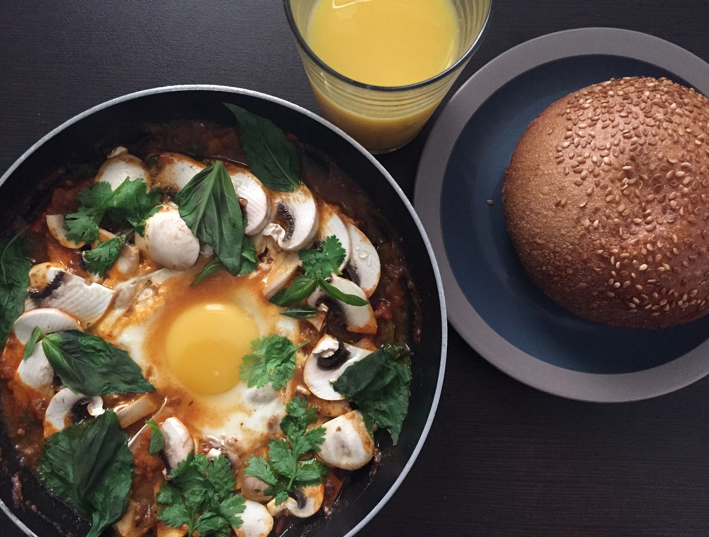 A vibrant shakshuka topped with sautéed mushrooms and garnished with fresh basil and cilantro, served with a seeded whole-grain roll. The dish captures the essence of creativity and fresh produce. This is another culinary highlight from The Liat Show and Foodie Disorder by Liat Portal.