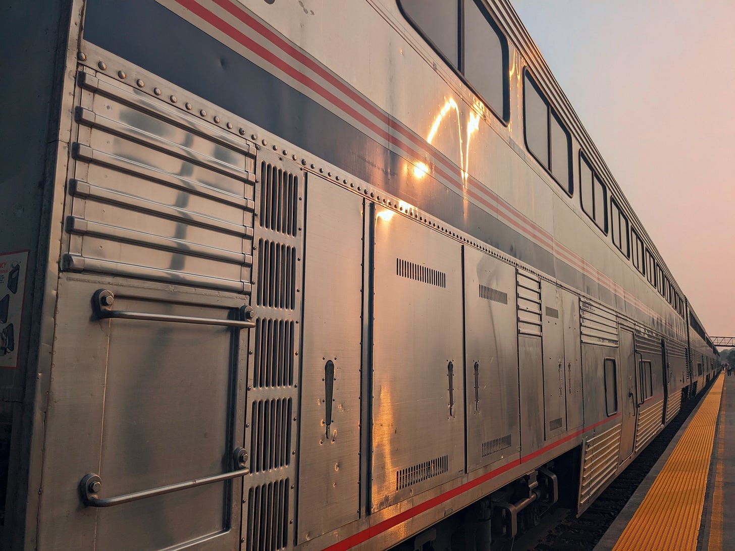 A photograph looking down the length of a two-story silver train.