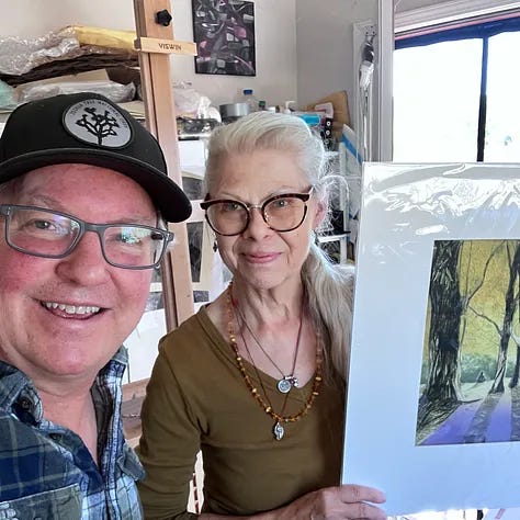 Man wearing glasses and Joshua Tree hat, Woman holding painting in art studio