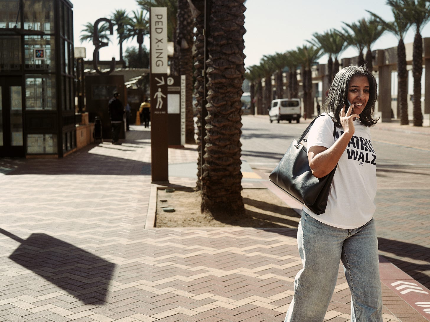 Woman on the phone wearing a Harris Walz campaign t-shirt walking outside Union Station in Los Angeles, by LA photographer Afonso Salcedo
