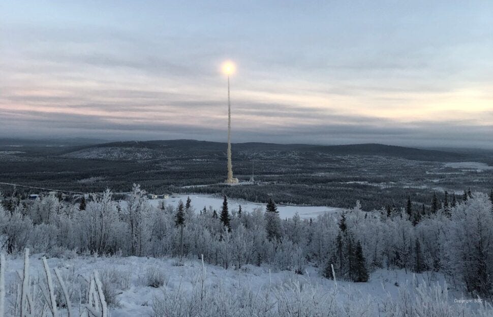 A rocket launch with a bright flame blasting from the engines, in contrast to the snowy trees of the surrounding landscape. 