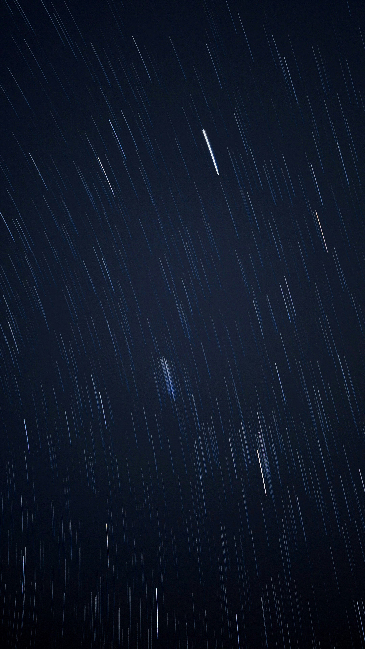Time-lapse photo of blurry orbiting stars in a night sky