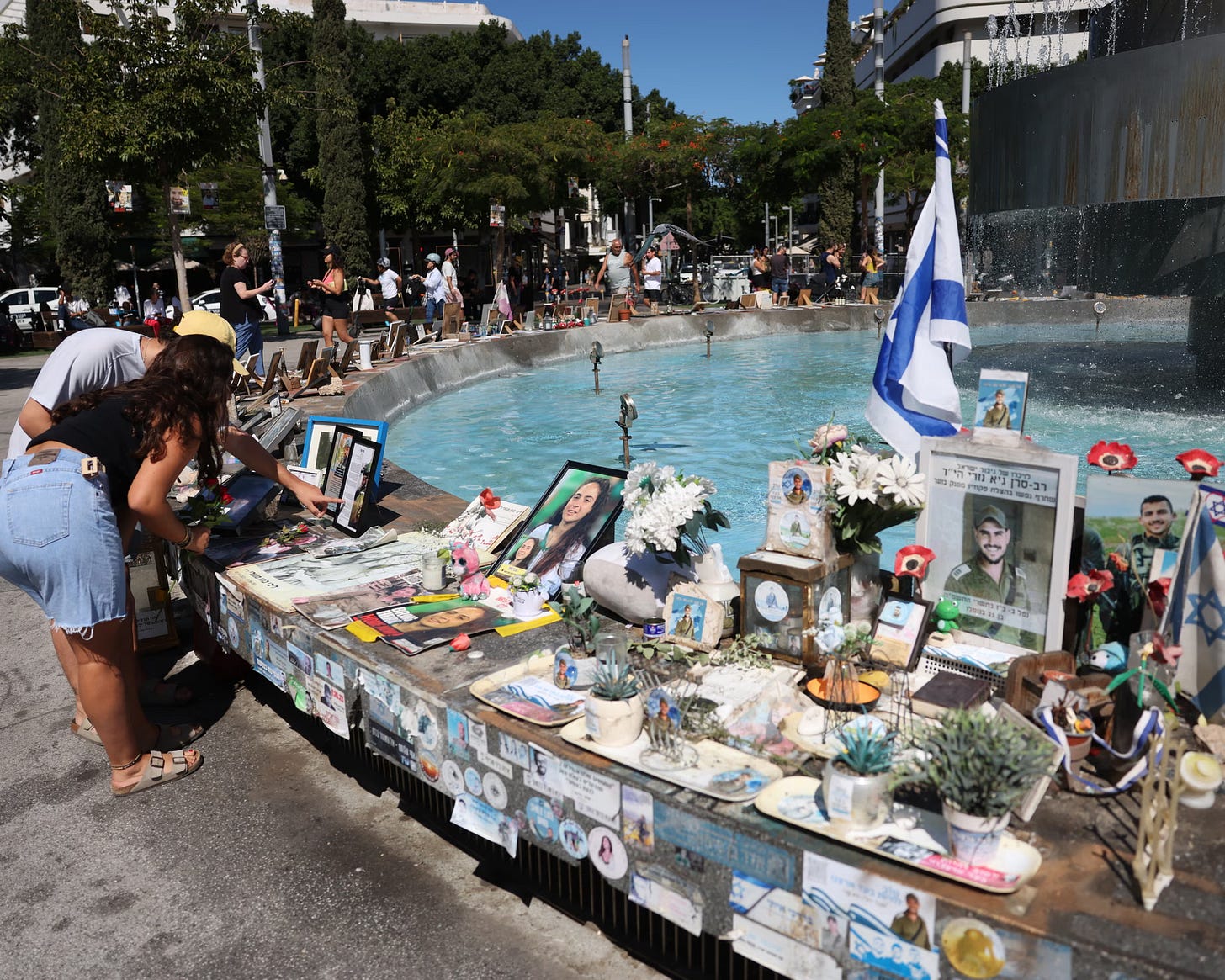 People in Dizengoff Square in Tel Aviv lay flowers near pictures and memorials of Israeli victims of the 7 October attack.