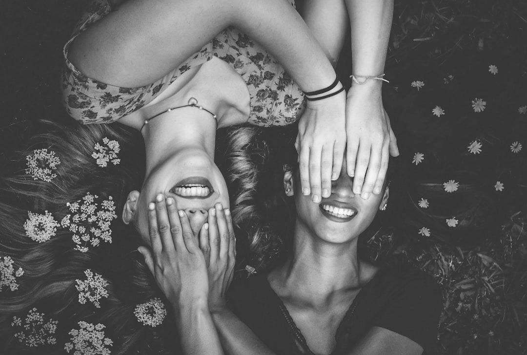 man and woman smiling while laying on lawn field man and woman smiling while laying on lawn field