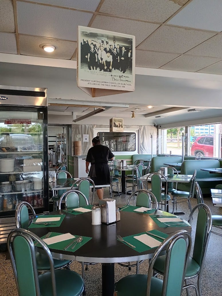 Inside of diner, with booths and round tables and chairs, a photo hanging over two tables