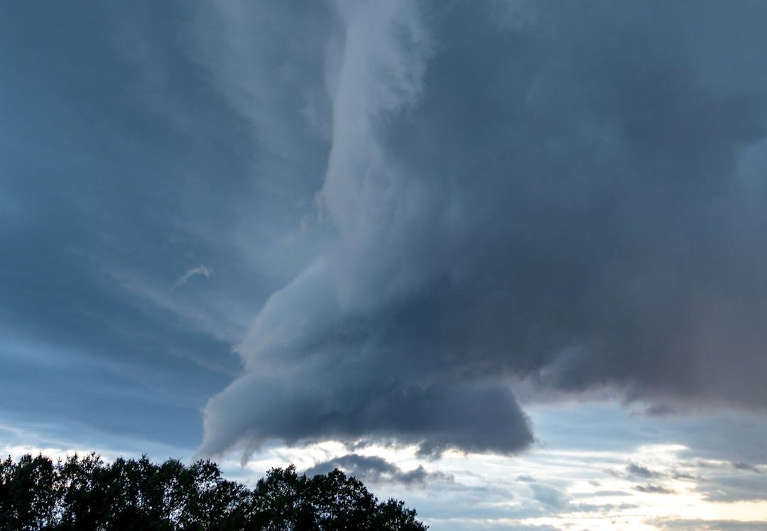 a large cloud is in the sky over a field